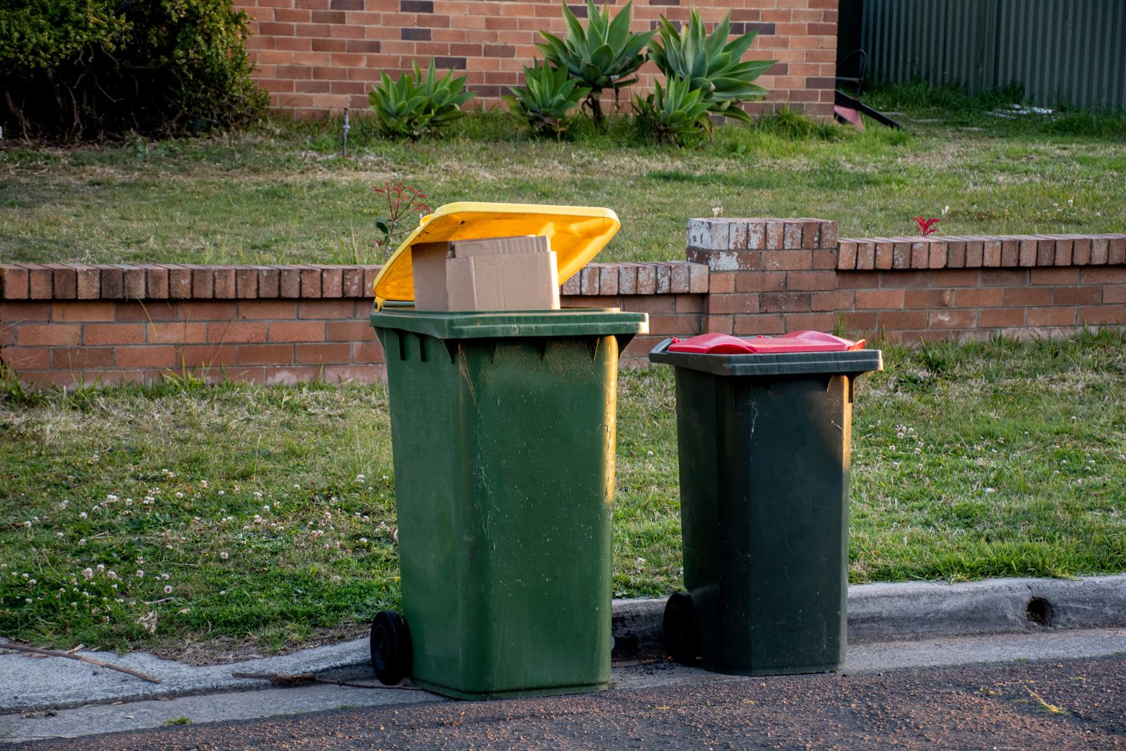 Australian Garbage Wheelie Bins With Colourful Lids For General And Recycling Household Waste On The Street Kerbside For Council Rubbish Collection.